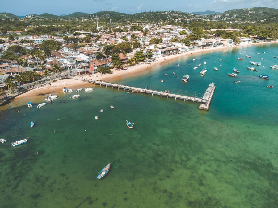 Vista aérea da orla de Búzios com barcos ancorados em água esverdeada